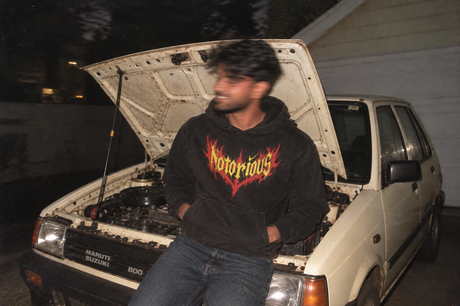 Fan in a black Notorious hoodie leaning on a car